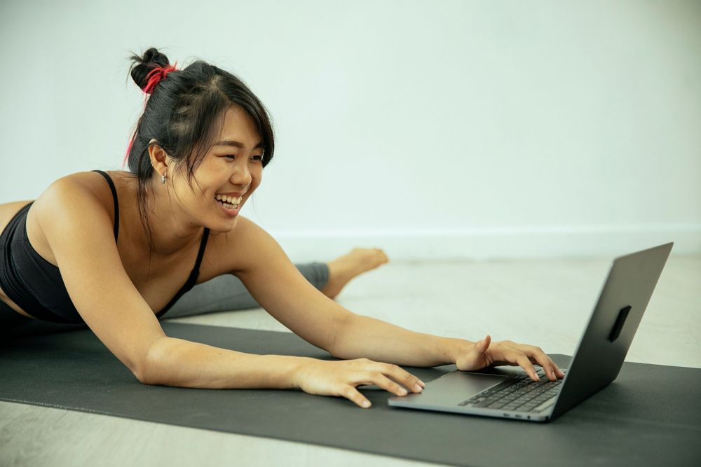 Team member working on a laptop from a yoga mat between meetings