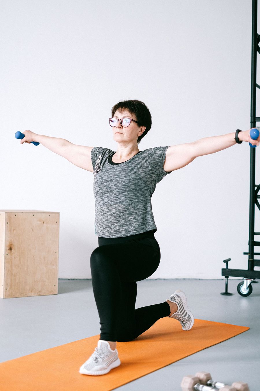 Employee doing a guided lunge with light dumbbells, wearing a fitness tracker