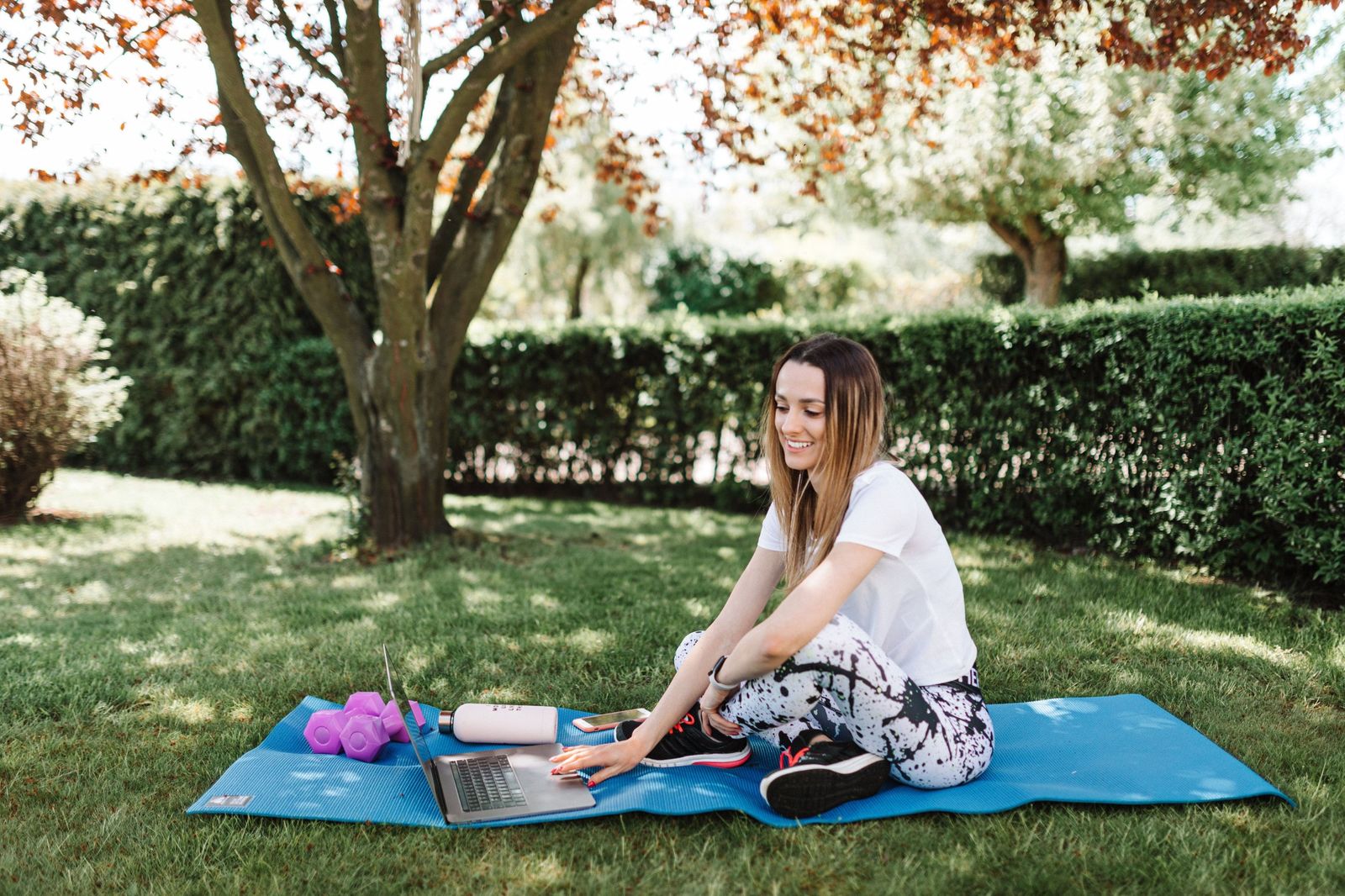 Employee taking a laptop work session outdoors on a mat between meetings